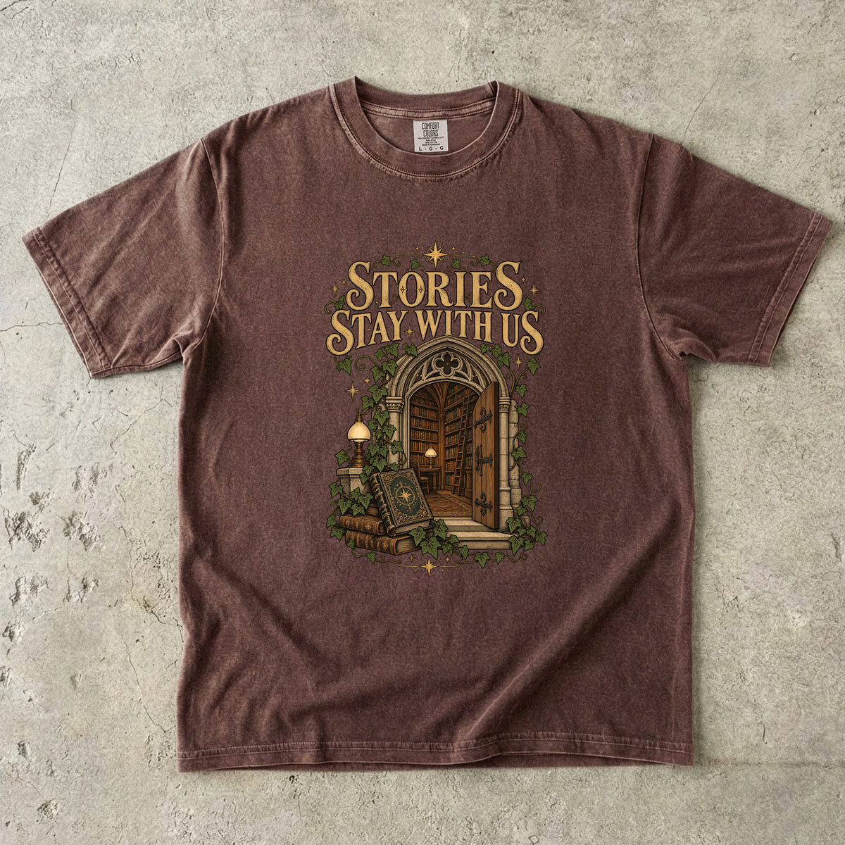 Espresso T-shirt featuring “Stories Stay With Us” with an ivy-covered arched library doorway, antique books, lamps and gold stars.