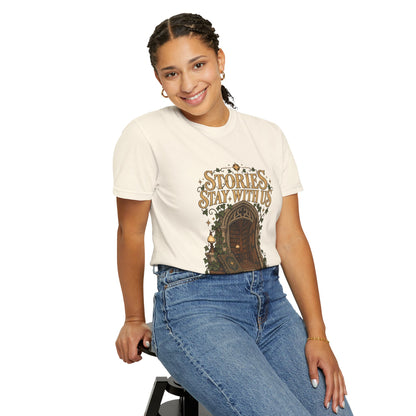 A woman wearing a ivory-colored graphic t-shirt with a brown door illustration and the text 'STORIES, STAY WITH US', paired with blue jeans, posing against a solid white background.