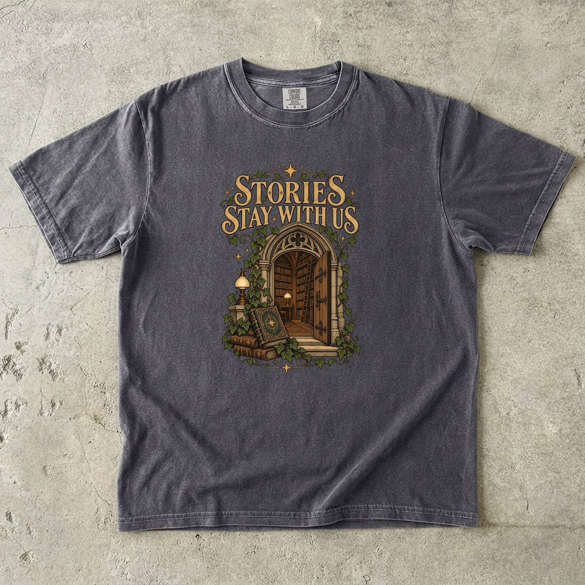 Pepper T-shirt featuring “Stories Stay With Us” with an ivy-covered arched library doorway, antique books, lamps and gold stars.