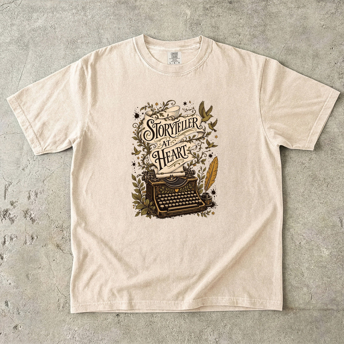 Storyteller at Heart writer shirt in Ivory featuring an ornate typewriter, manuscript ribbon, quill and botanical details.