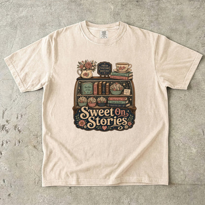 Sweet on Stories book lover T-shirt in Ivory featuring a vintage fresh-fiction display with books, page cakes, flowers and teacup