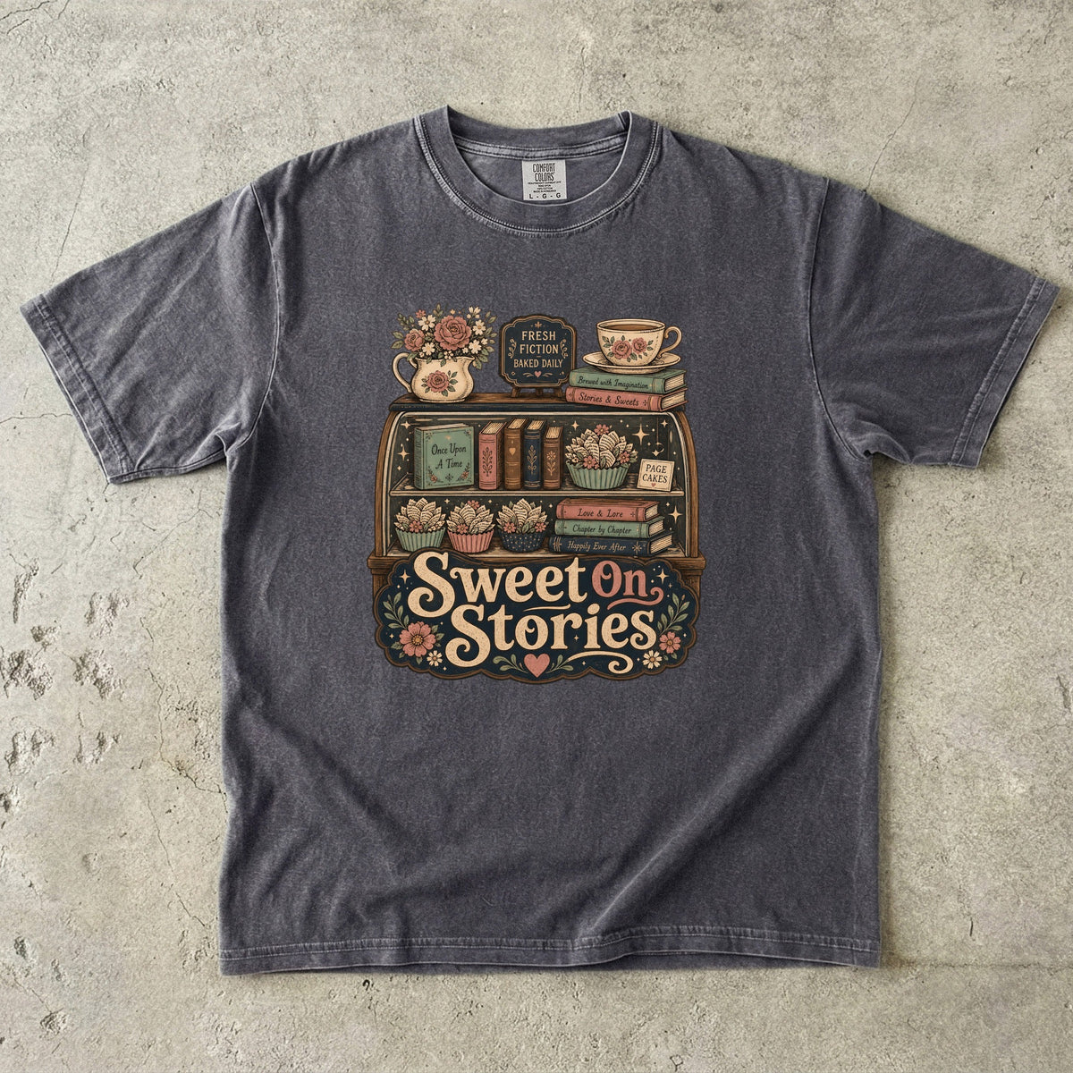Sweet on Stories book lover T-shirt in Pepper featuring a vintage fresh-fiction display with books, page cakes, flowers and teacup