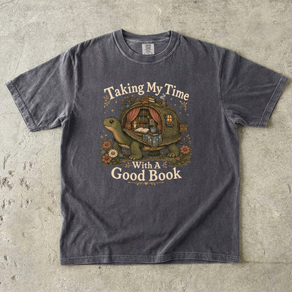 Taking My Time With a Good Book T-shirt in Pepper featuring a tortoise carrying a cozy book-filled reading retreat