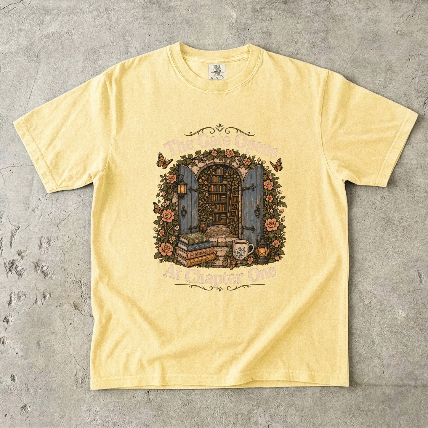 The Gate Opens at Chapter One literary T-shirt in Butter featuring open blue gates leading into a flower-filled hidden library
