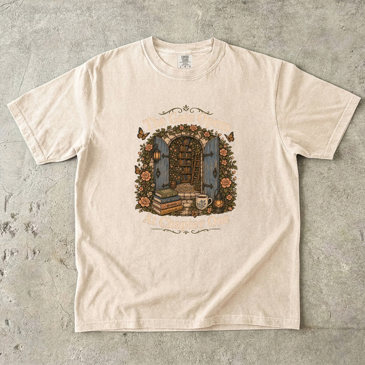 The Gate Opens at Chapter One literary T-shirt in Ivory featuring open blue gates leading into a flower-filled hidden library