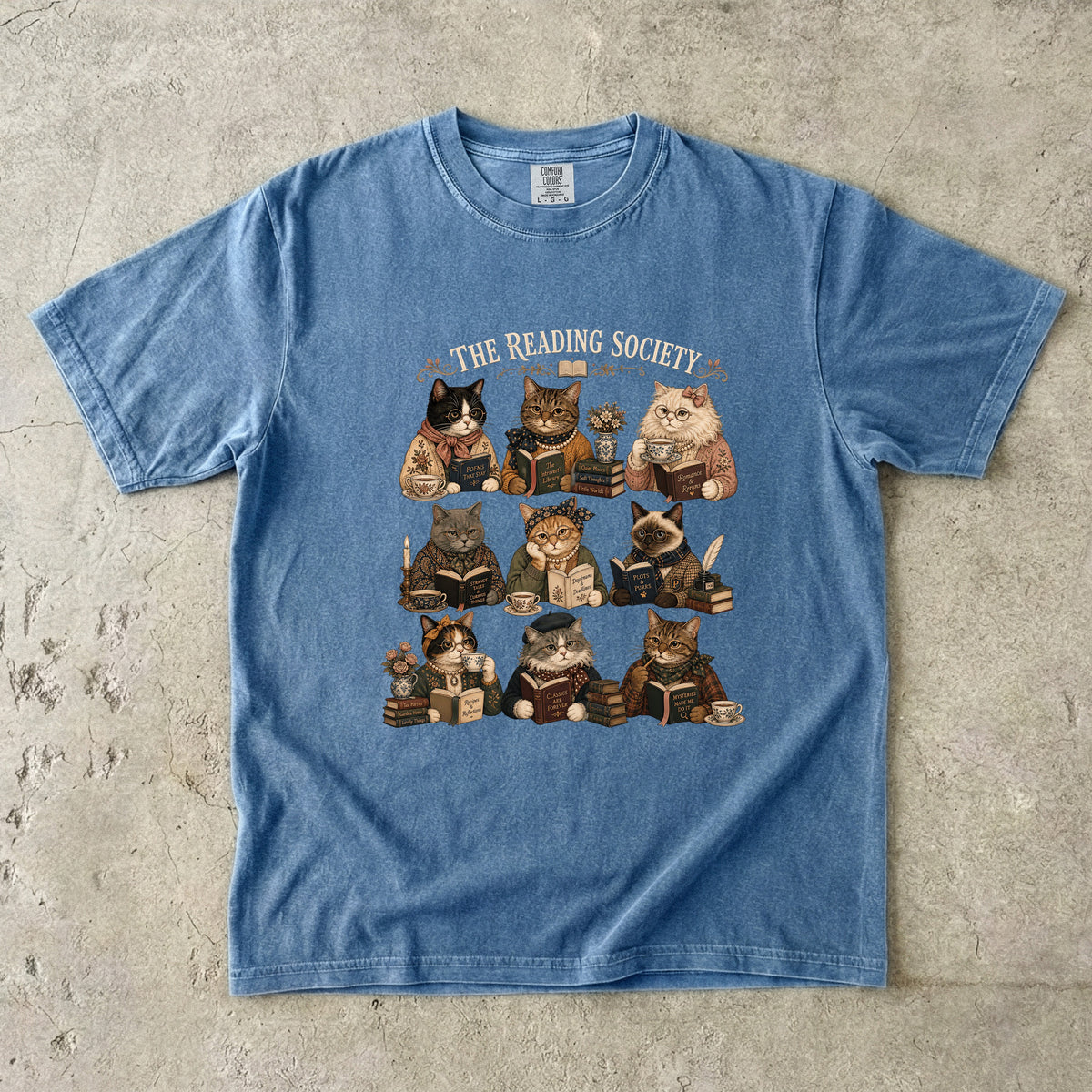 The Reading Society cat book club T-shirt in Blue Jean featuring nine cats reading books with teacups and vintage accessories