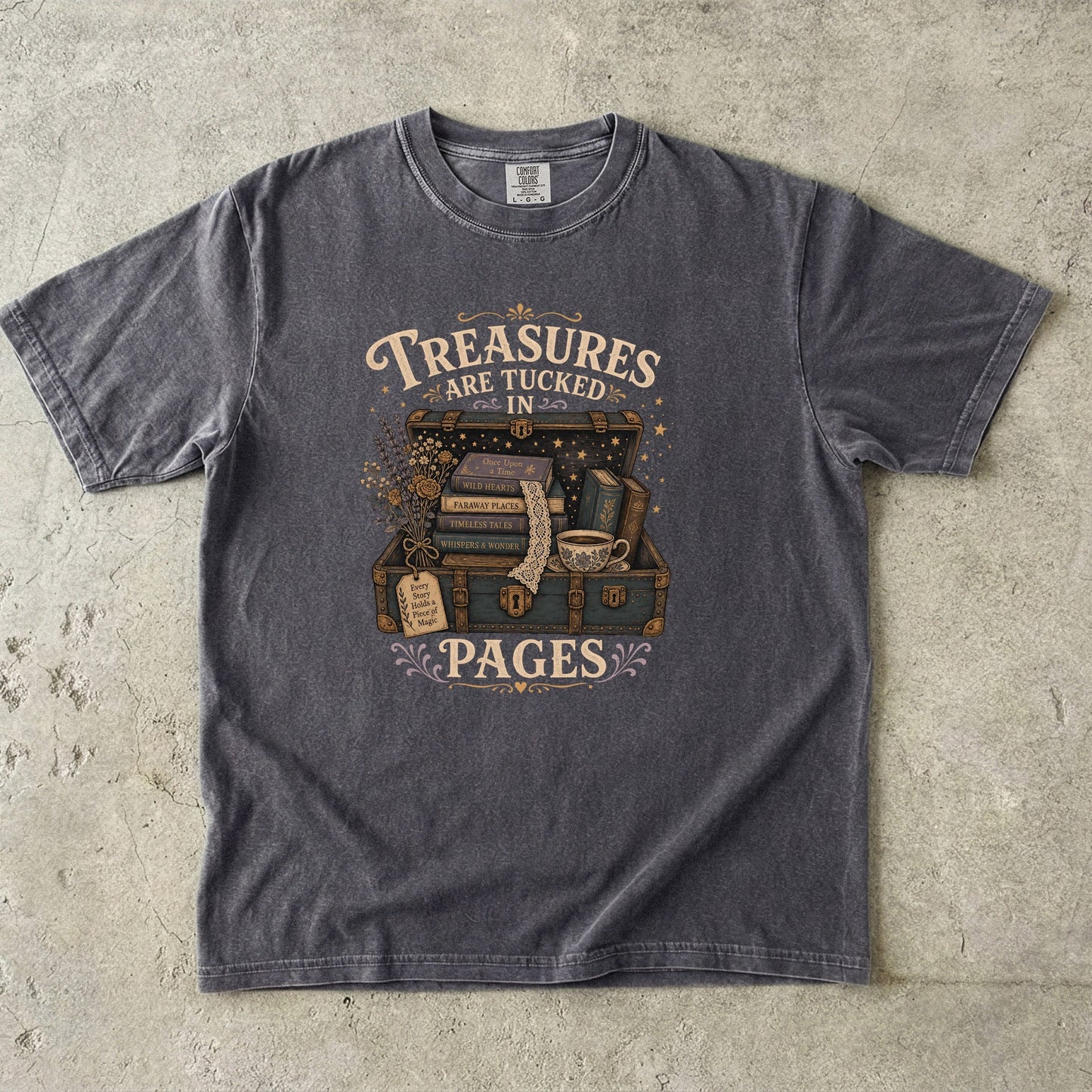 Front view of the Comfort Colors 1717 T-shirt in Pepper featuring the "Treasures Are Tucked in Pages" vintage illustration with an open treasure chest, books, flowers and a teacup. 

