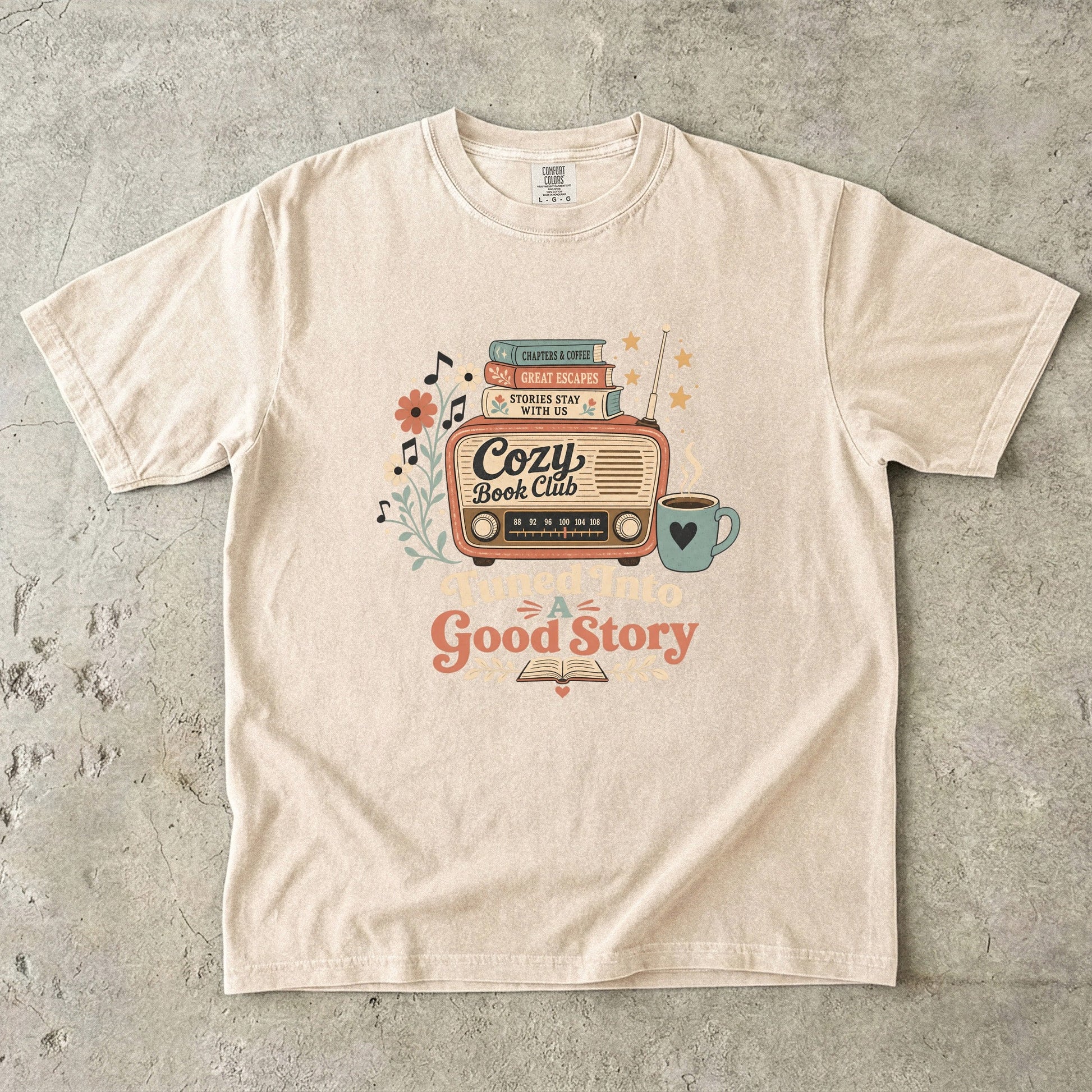 Front view of an Ivory Comfort Colors Book Lover T-shirt featuring the Tuned Into a Good Story artwork.