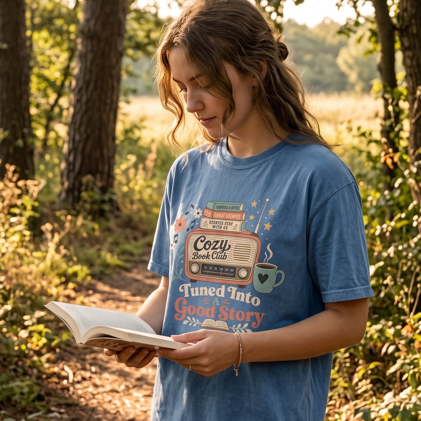 Woman wearing the Tuned Into a Good Story Comfort Colors Book Lover T-shirt while reading outdoors with a cozy vintage aesthetic.