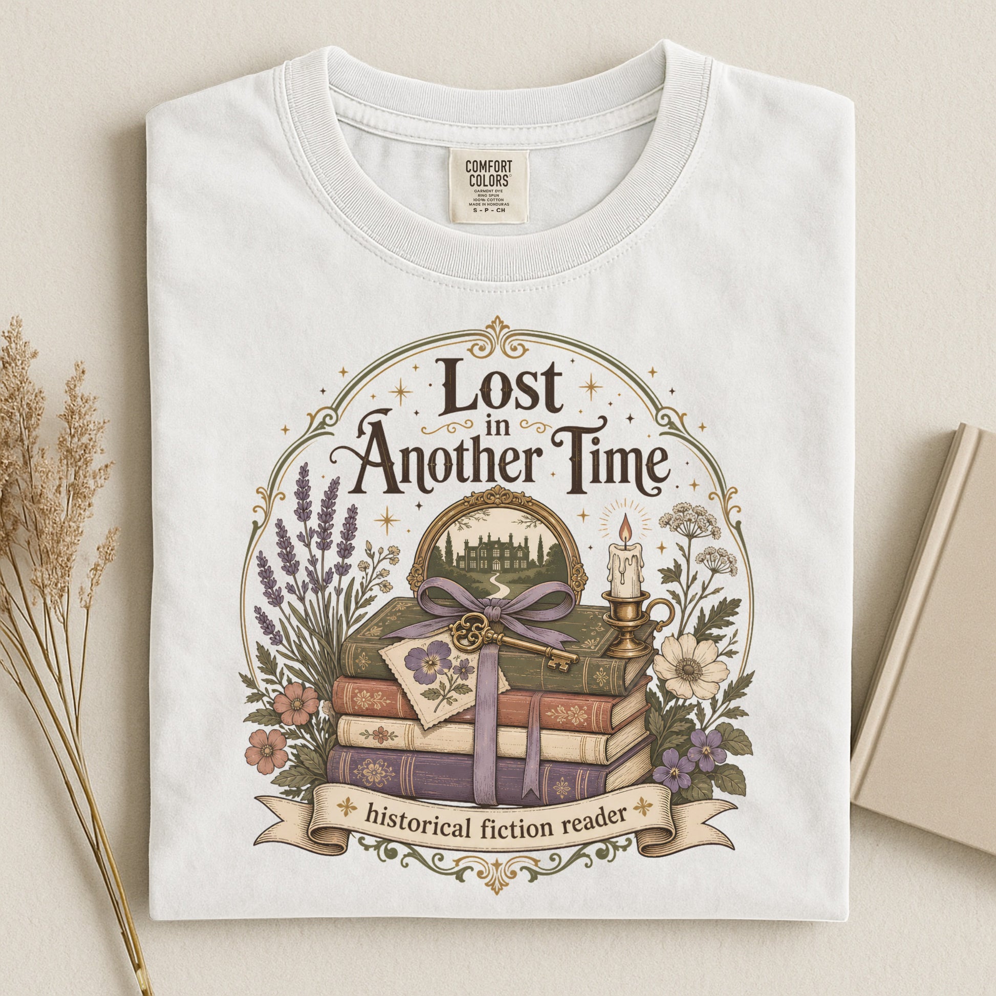 Folded white Comfort Colors reading shirt displaying vintage literary artwork with books and florals.